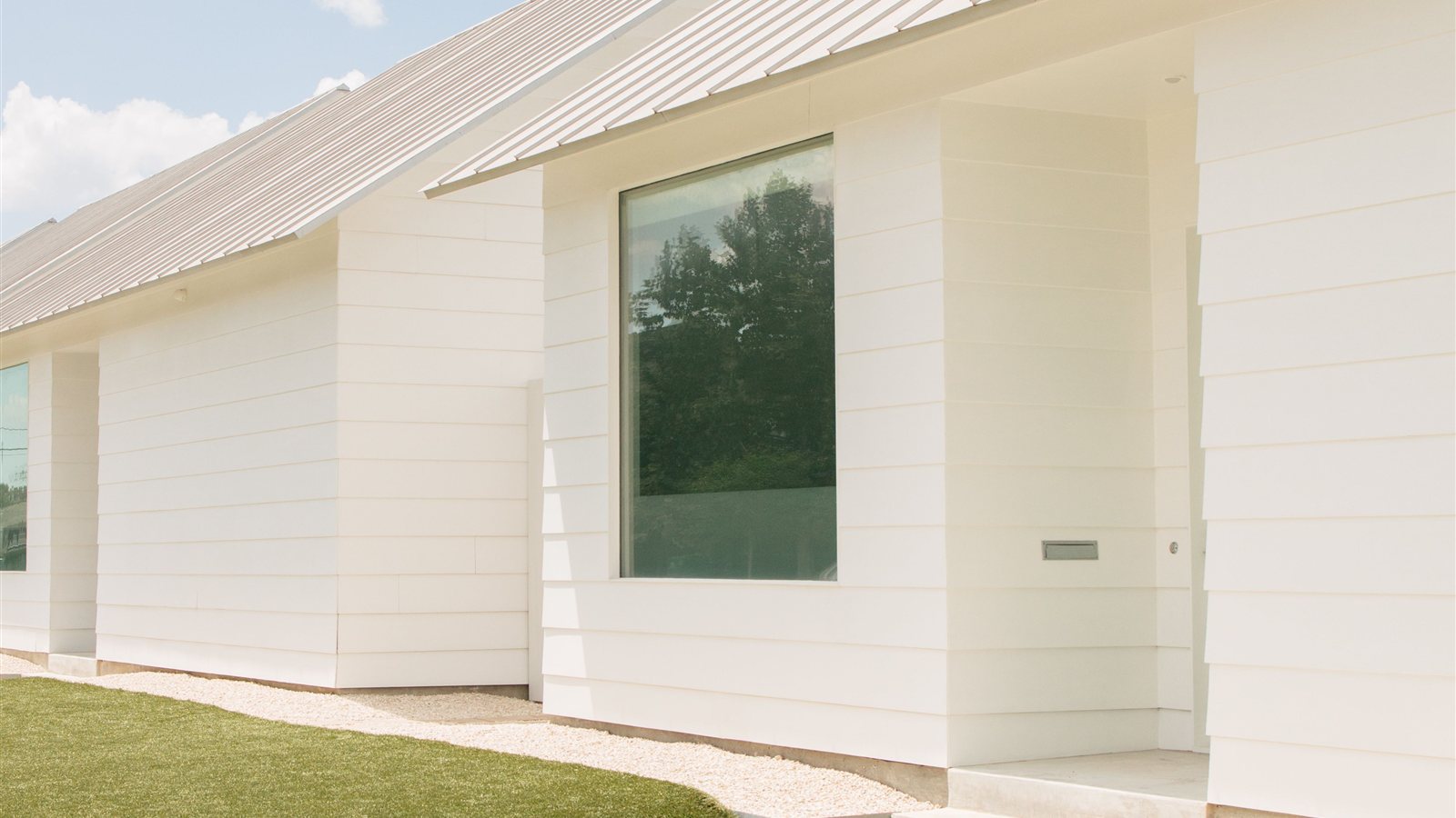 Modern white Texas home exterior with large glass windows, representing a move-up buyer property in the San Antonio area.