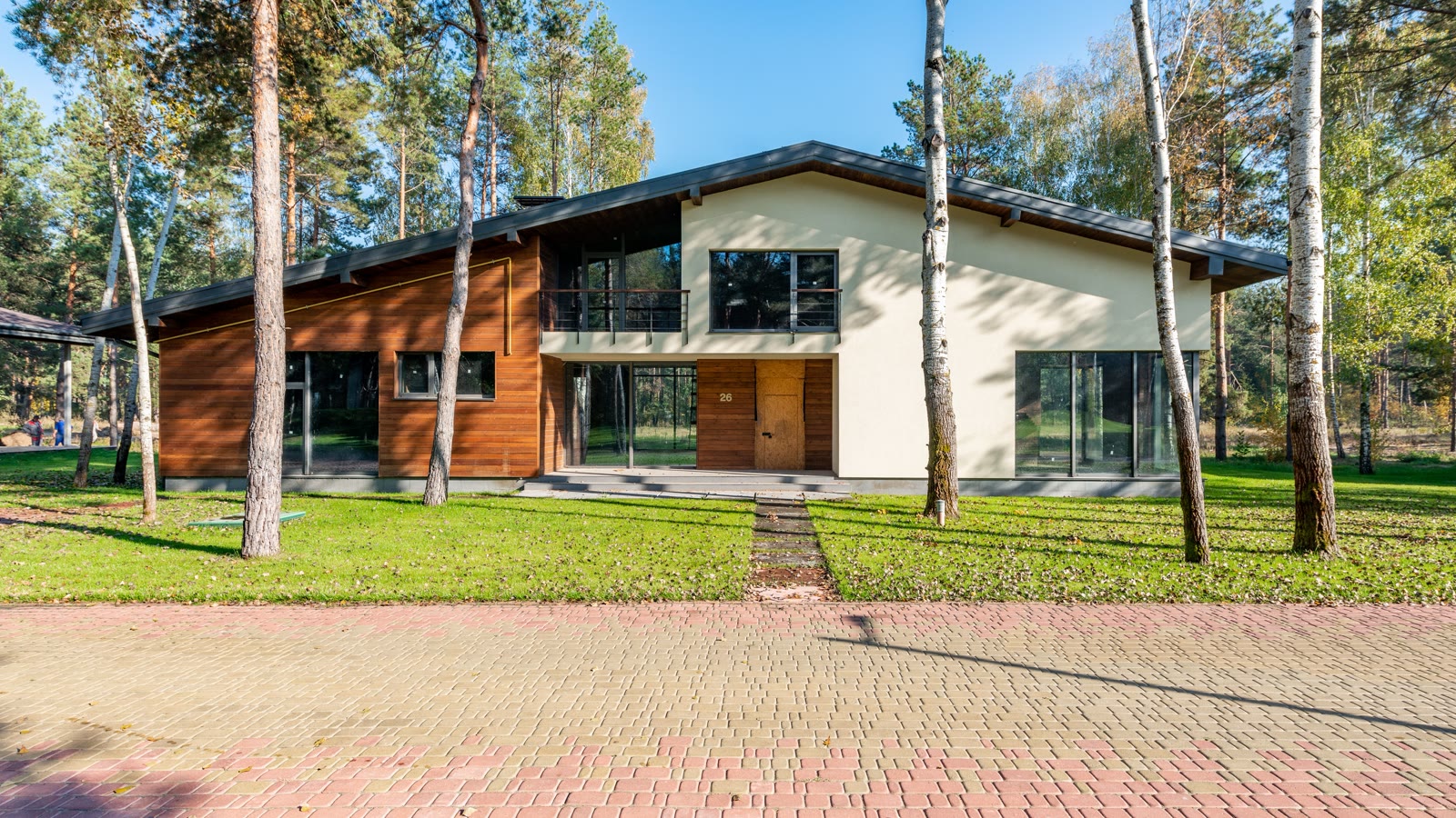 A modern two-story home surrounded by trees and a landscaped lawn.